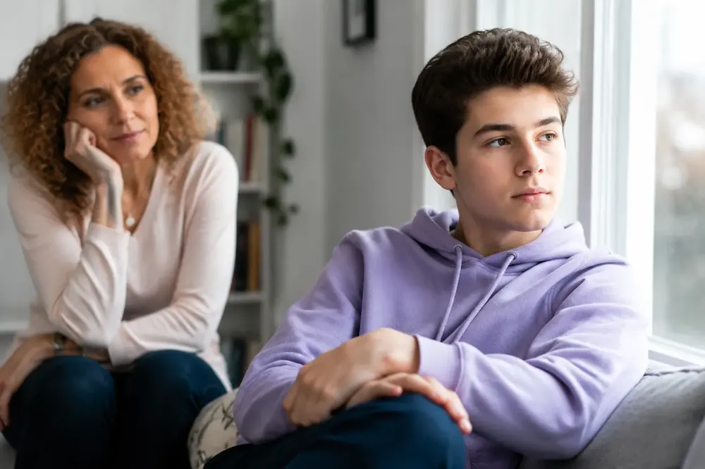 Ilustração de uma adolescente chorando, sentada e abraçando as pernas, representando o sofrimento psíquico na depressão na adolescência.